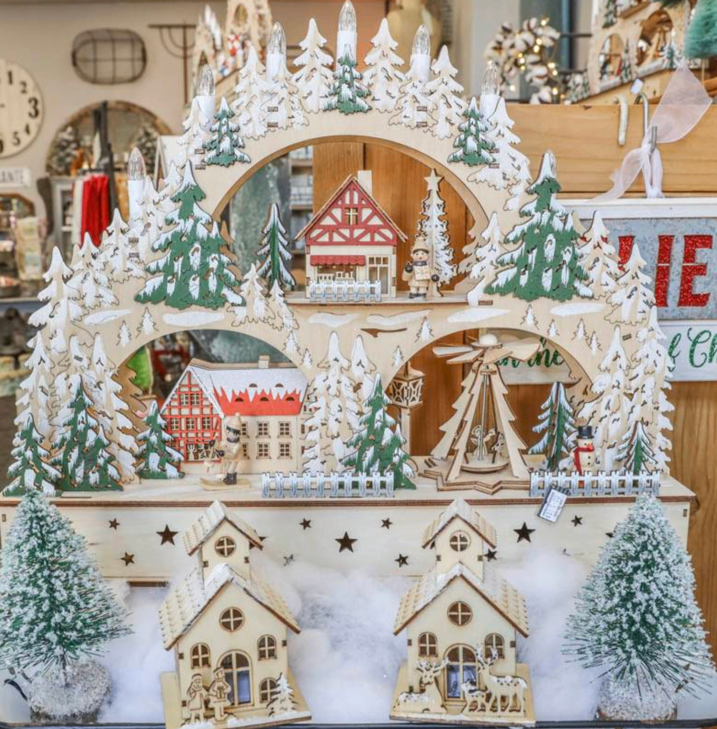 Wooden lit holiday village display with snow-covered trees and cottages.